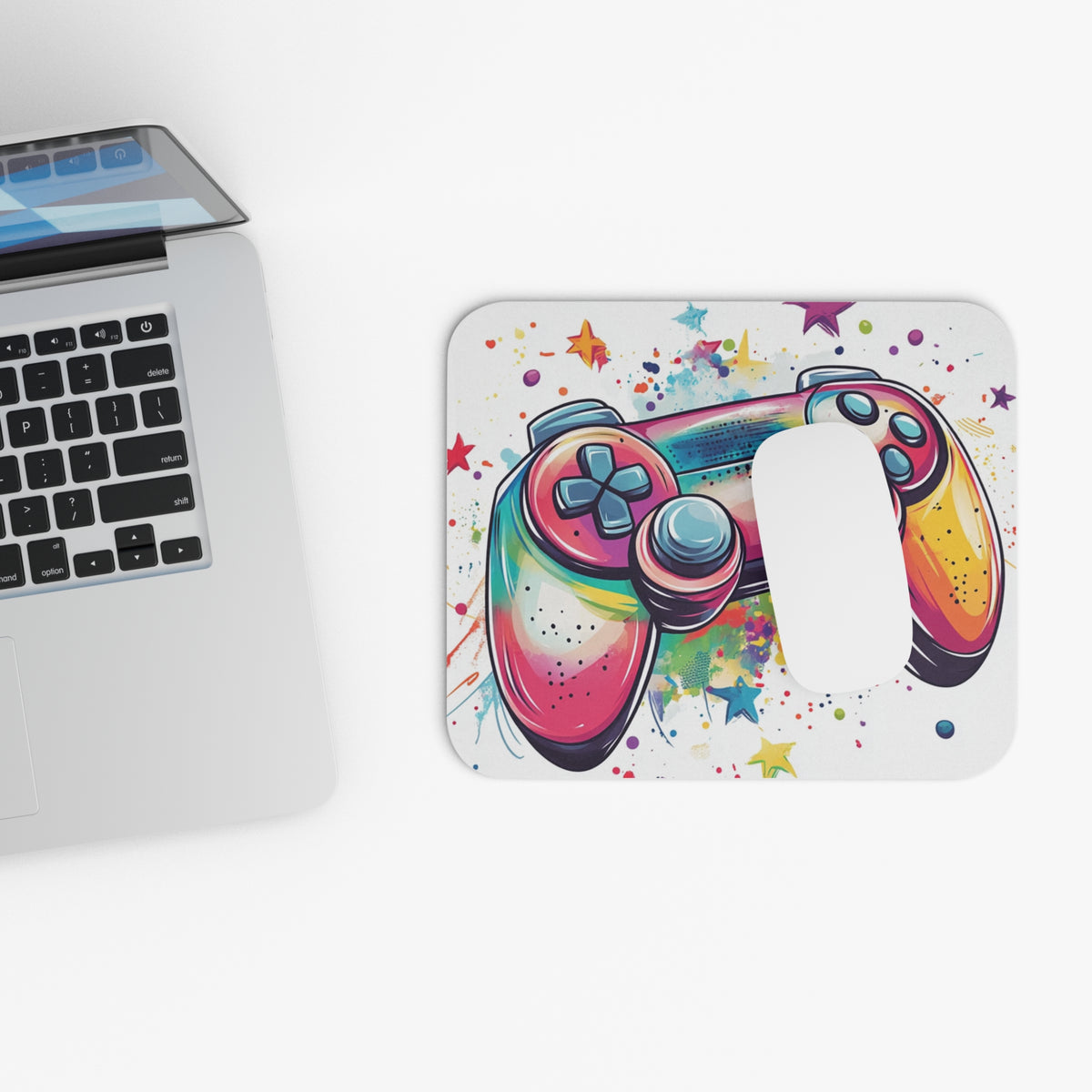 Colorful gamepad design on a rounded rectangular mousepad next to a laptop.