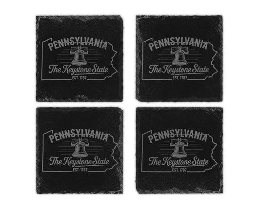 Four black slate coasters featuring Pennsylvania outline, Liberty Bell, and "The Keystone State".