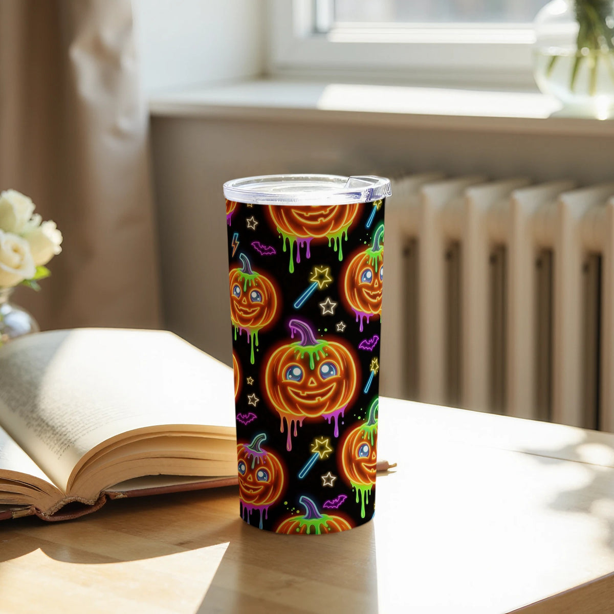 Tumbler with a repeating pattern of glowing neon Halloween pumpkins, bats, and stars on a black background.