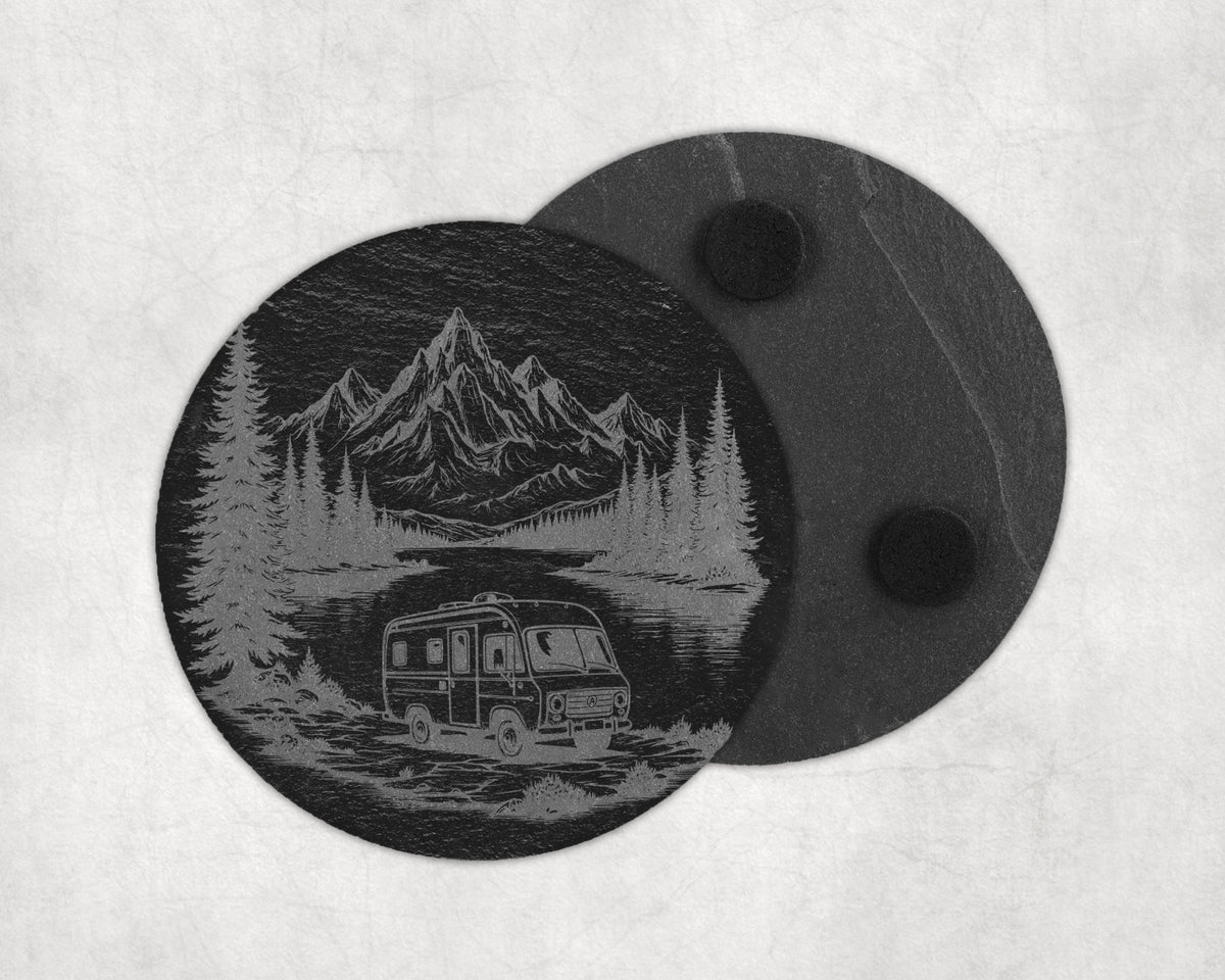 Circular coaster with engraved mountain, forest, and camper scene.