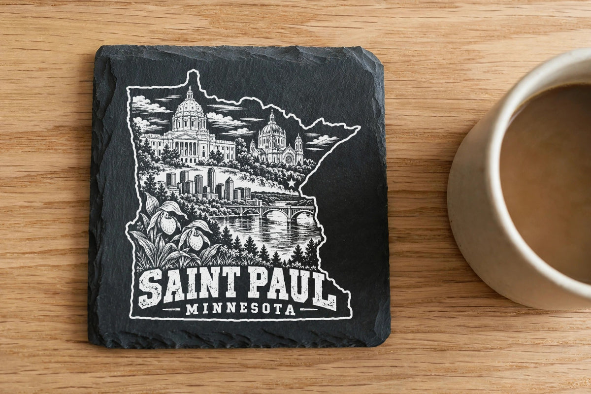 Square slate coaster featuring an engraved white illustration of Saint Paul, Minnesota, next to a coffee mug.