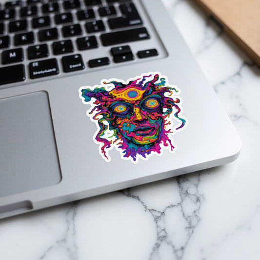 Vibrantly colored abstract face sticker with multiple eyes on a laptop keyboard.