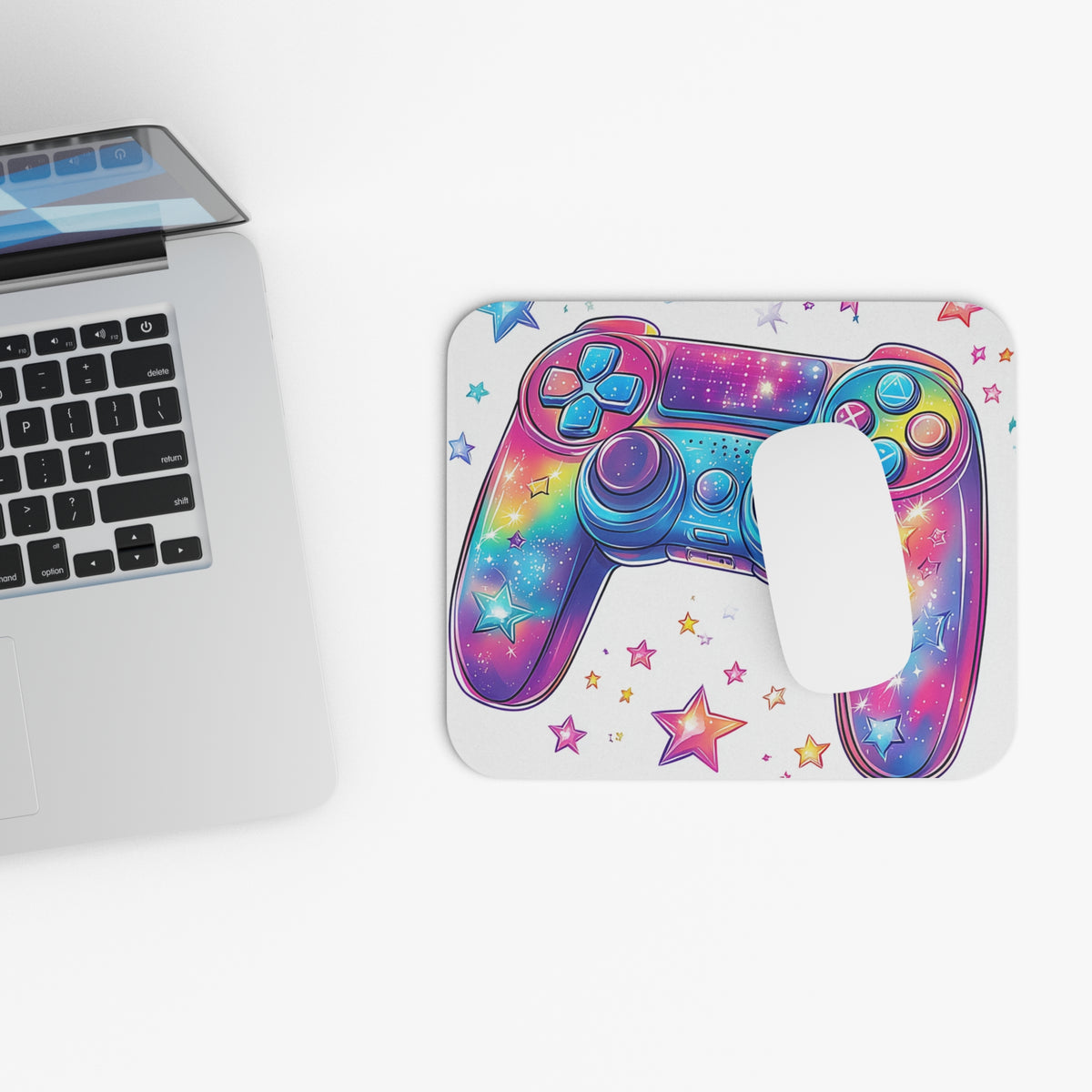 Colorful galaxy controller design on a white mousepad with stars, next to a laptop.