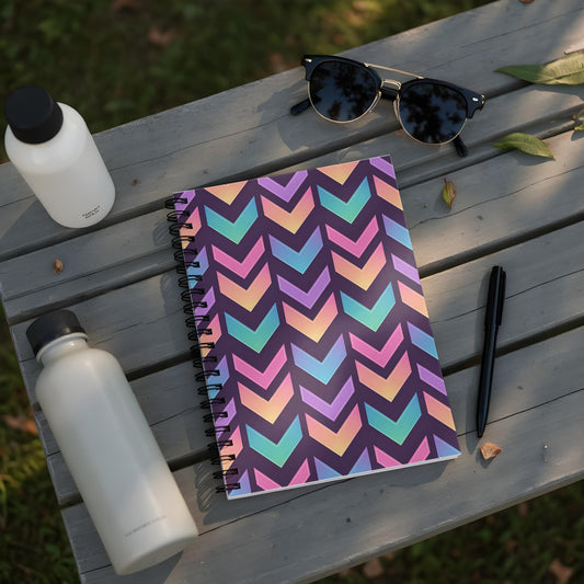 Spiral notebook with chevron pattern, two water bottles, sunglasses, and pen on a bench.
