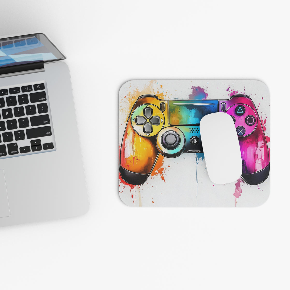 Gaming controller with watercolor splash design on a mousepad next to a laptop.