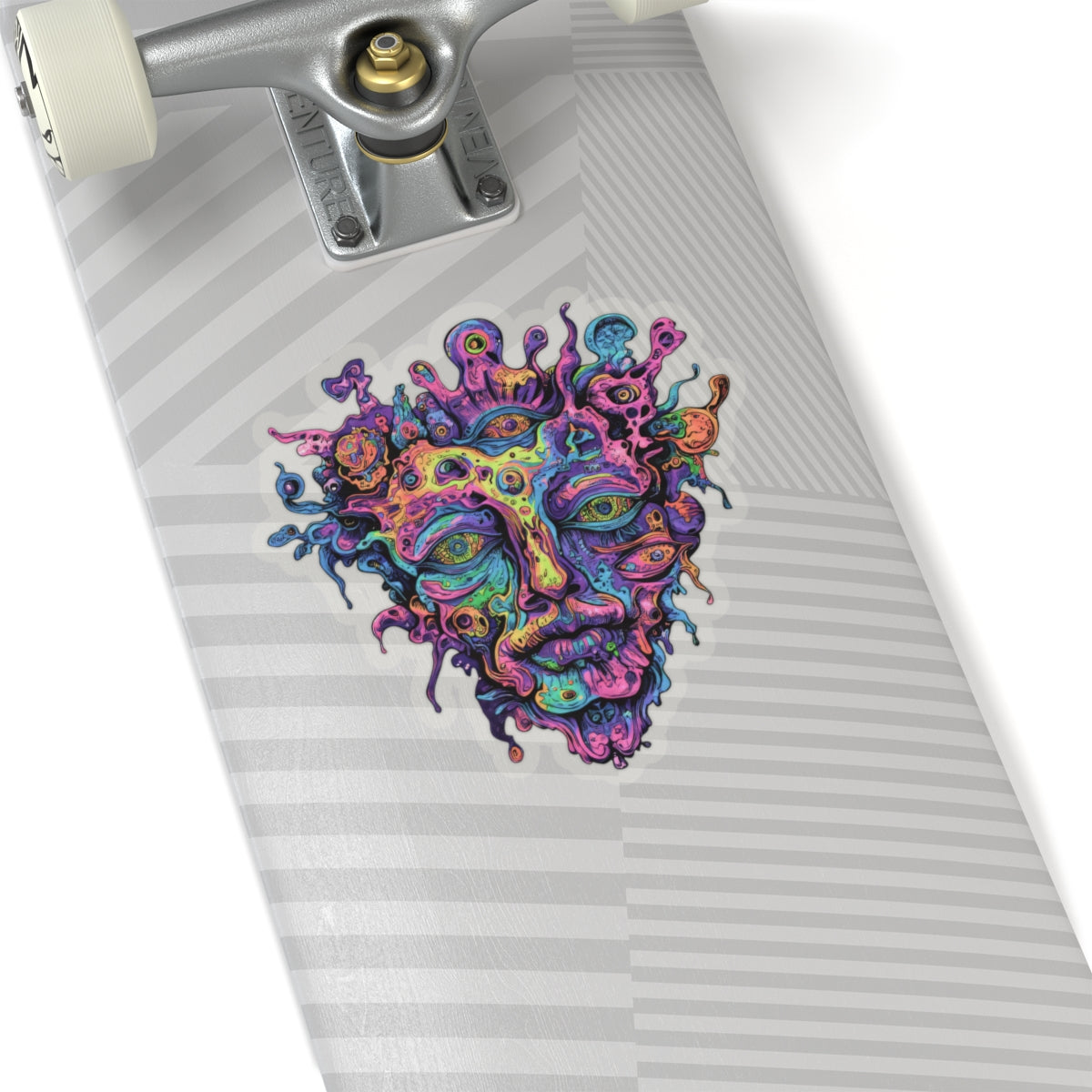 Colorful psychedelic face sticker on a skateboard deck with grey striped grip tape.
