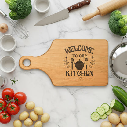 Wooden cutting board with "Welcome to our kitchen" engraving surrounded by fresh ingredients.