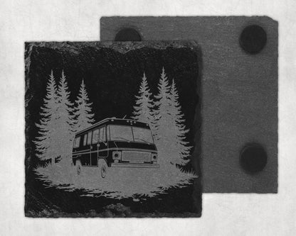 Slate coaster with engraved RV in a forest scene and a second coaster behind.