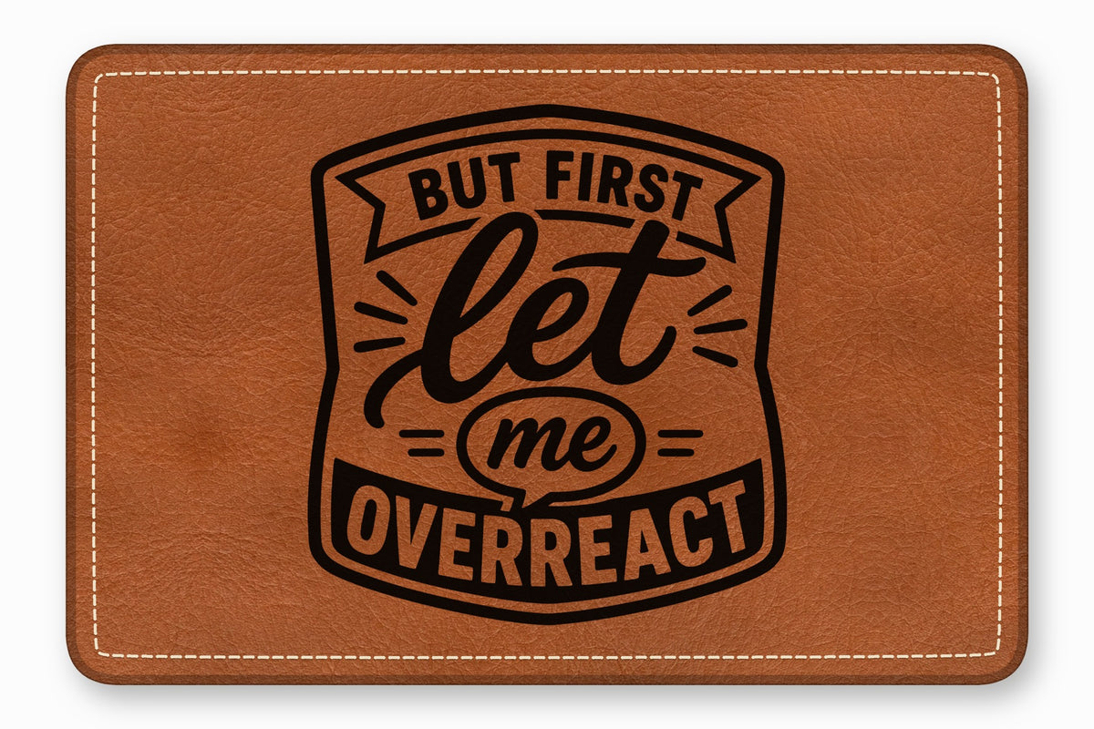 Brown rectangular leather patch featuring white border stitching and the black text But First Let Me Overreact.