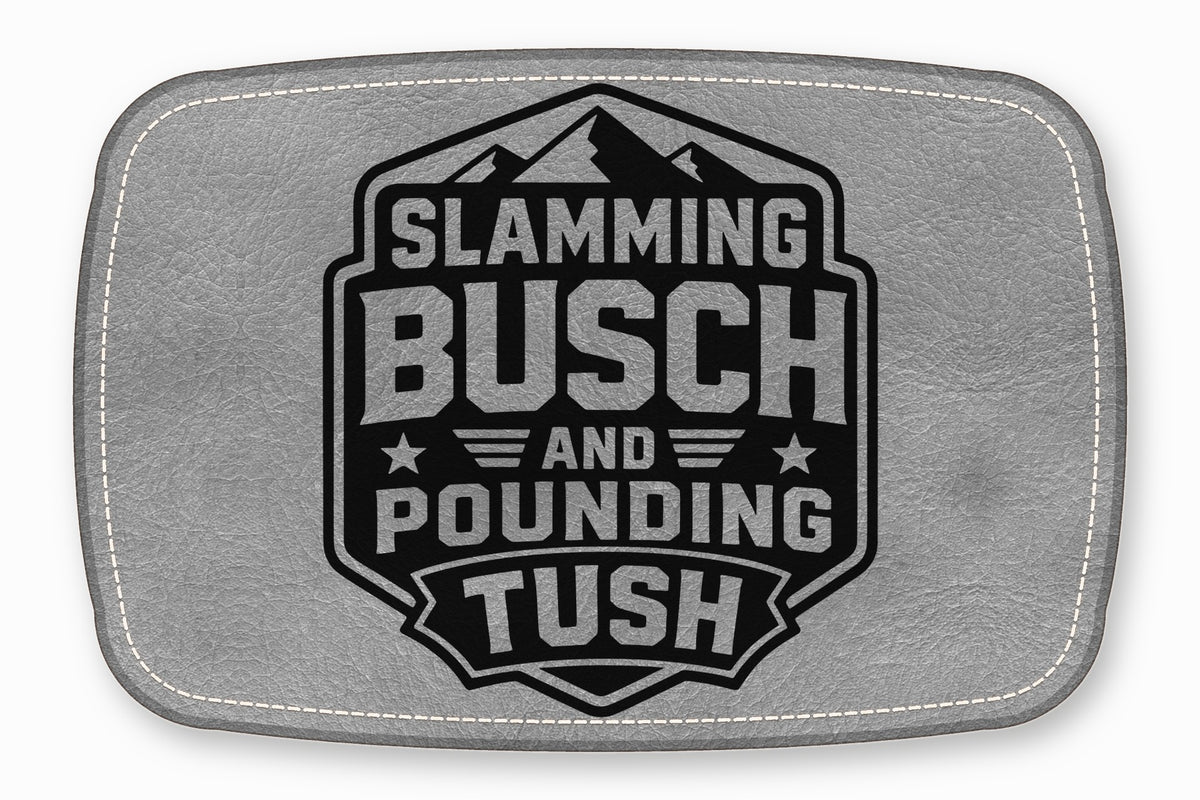Gray leather patch with rounded corners, white stitching, and a black mountain emblem reading Slamming Busch and Pounding Tush.