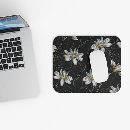 Black mousepad with a white floral pattern and gold accents, next to a laptop.
