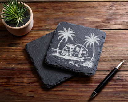 Slate coaster with etched caravan and palm trees design, next to a pen.