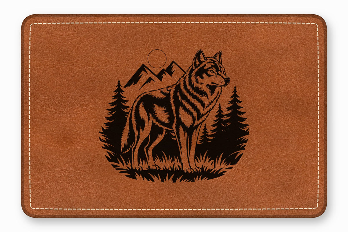 Brown leather mouse pad featuring a black engraved design of a wolf, mountains, and pine trees.