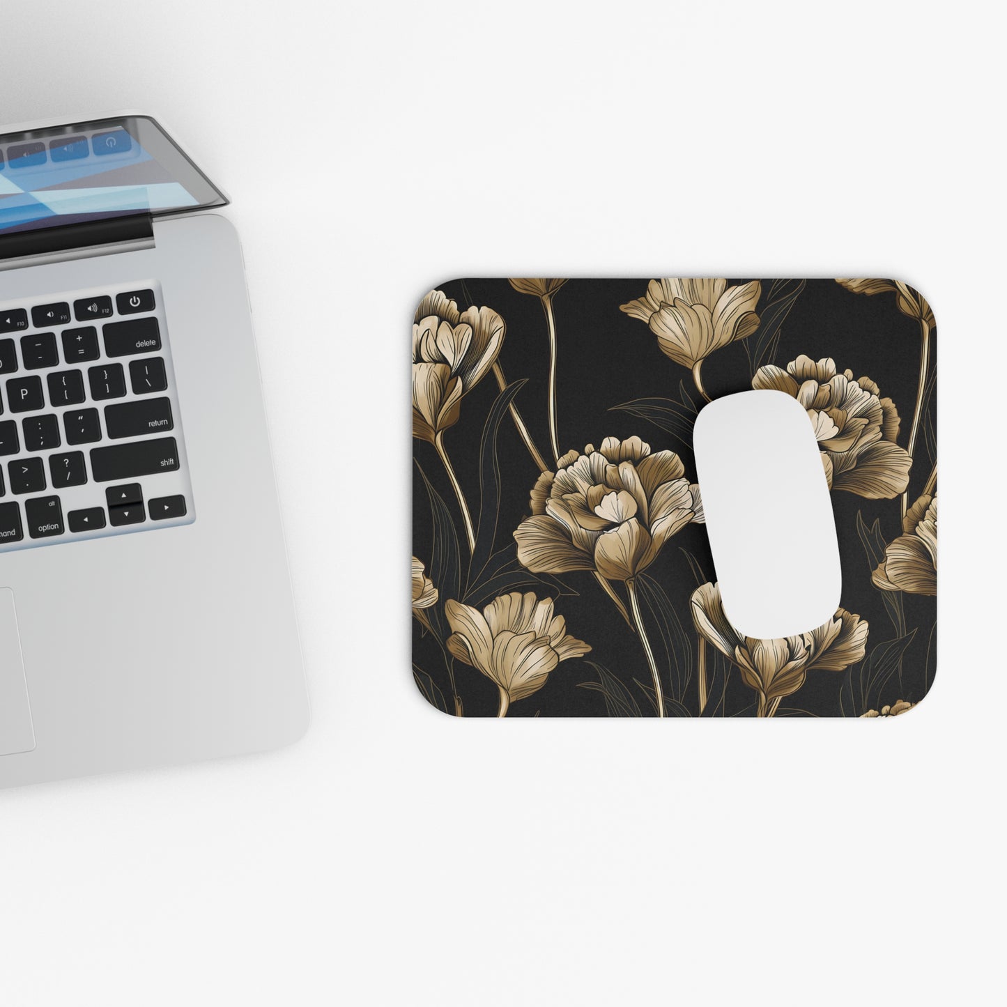 Mousepad with gold floral pattern on black, next to a laptop.
