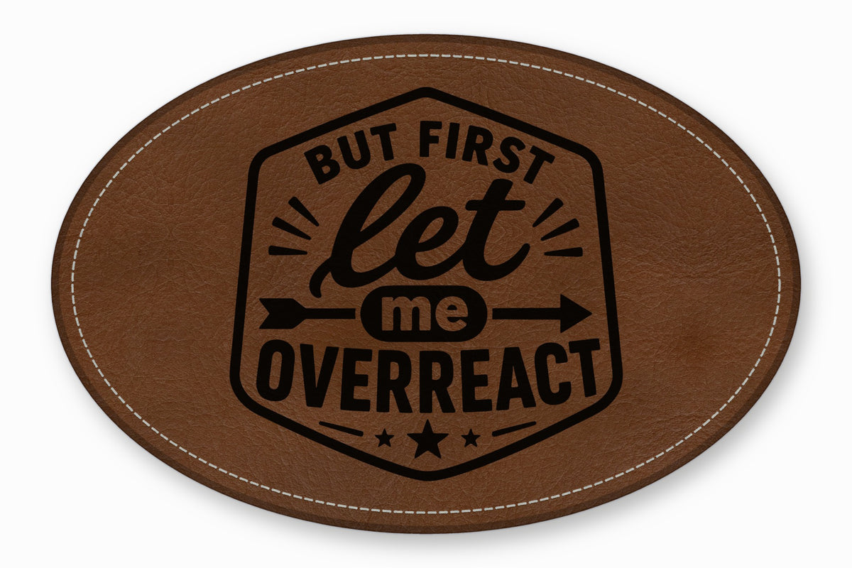 Brown oval leather patch featuring stitched edges and black text that reads But First Let Me Overreact.