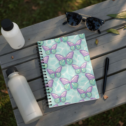 Spiral notebook with purple and teal butterflies on a light blue water-like background.