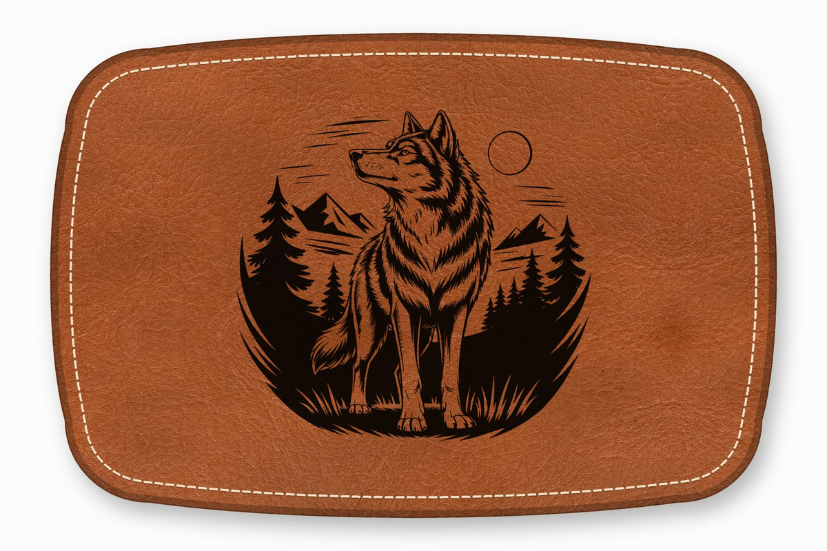 Brown leather patch with rounded corners, white decorative stitching, and a black engraved wolf landscape graphic.
