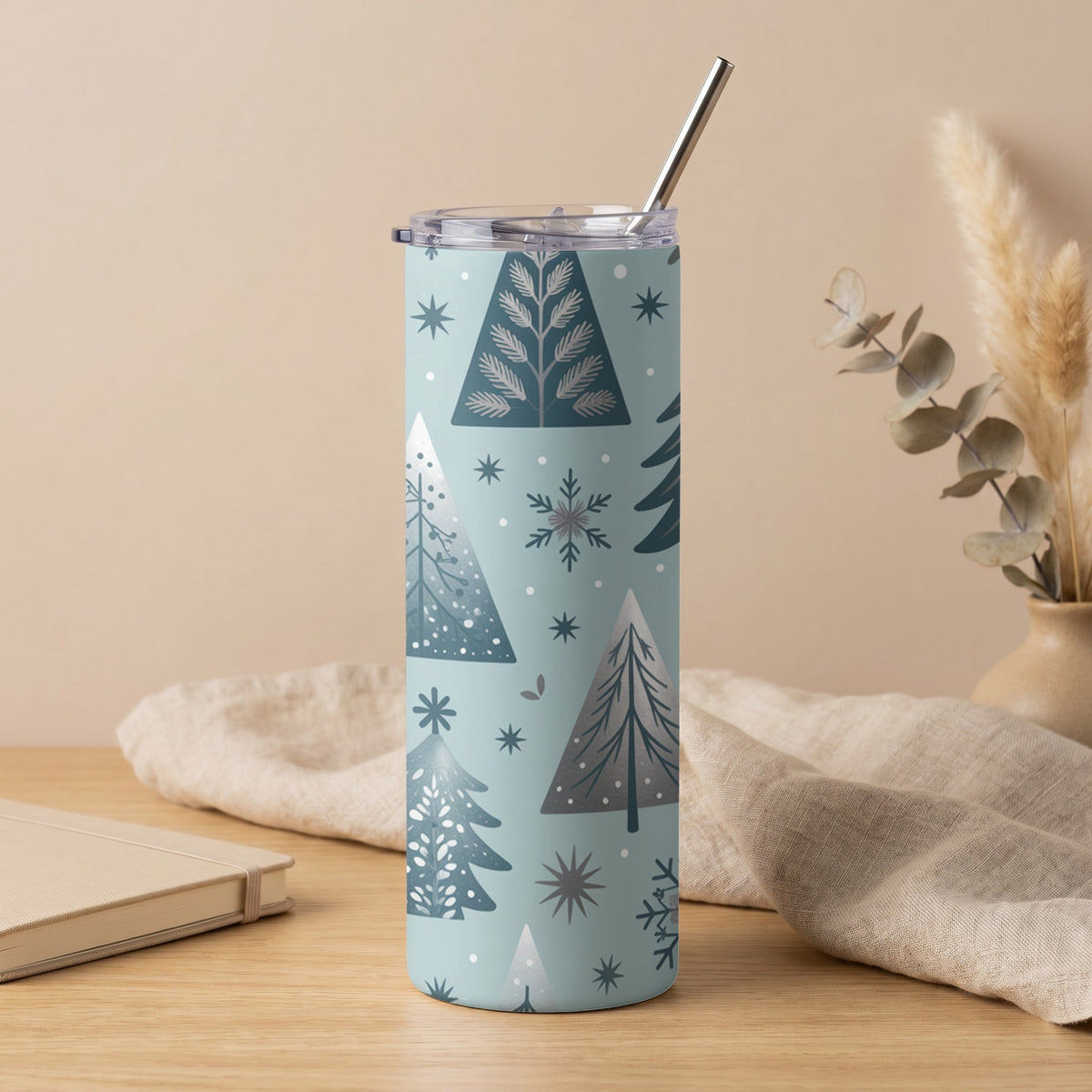 Light blue tumbler with gray trees, snowflakes, and stars pattern and silver straw.