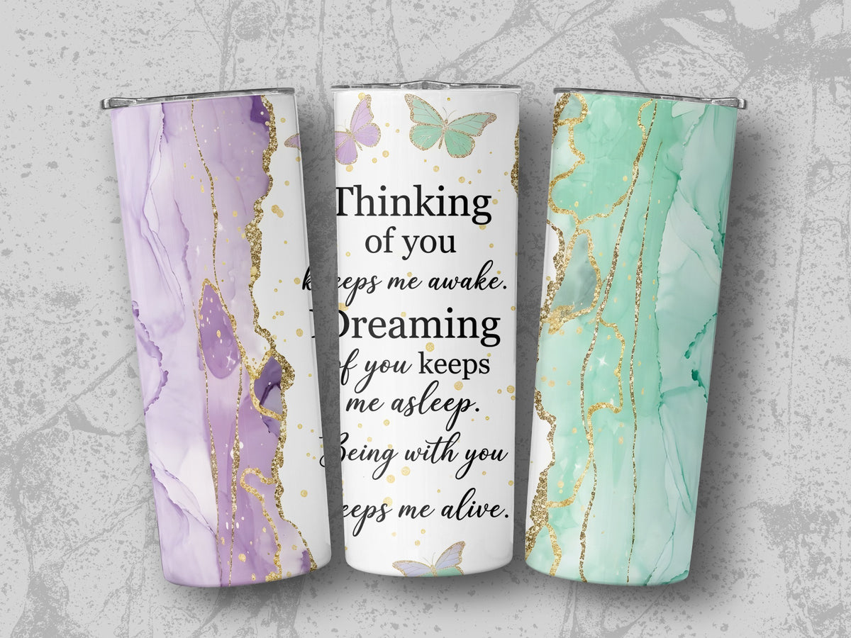 Three tumblers with marble patterns and gold accents, one with quote "Thinking of you".