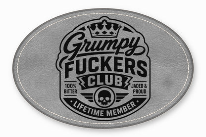 Oval gray faux leather patch with black embroidered text reading Grumpy Fuckers Club, crown, and skull.