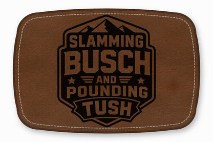 Brown rectangular faux leather patch with white stitching and a black engraved mountain logo and text reading Slamming Busch and Pounding Tush.