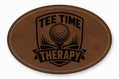 Brown oval leather patch featuring a black embroidered design with a golf ball and the text Tee Time Therapy.