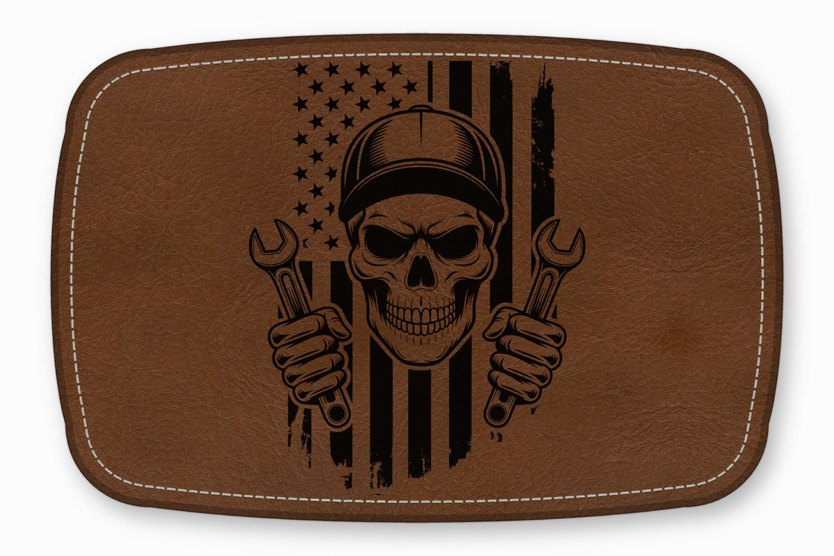 Brown leather patch featuring a black engraved mechanic skull holding wrenches against an American flag.
