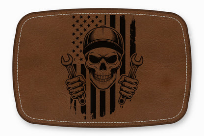Brown leather patch featuring a black engraved mechanic skull holding wrenches against an American flag.