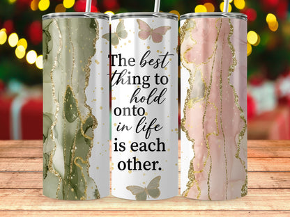 Three tumblers with abstract marbling, glitter accents, and the quote "The best thing to hold onto in life is each other."