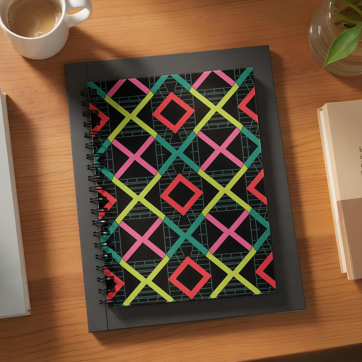 Spiral-bound notebook with a black cover featuring a geometric diamond pattern in pink, lime green, and teal.