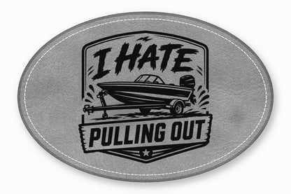 An oval gray leather patch with white stitching featuring a boat graphic and the text I HATE PULLING OUT.