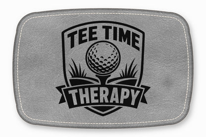 A grey leather patch with white stitched borders and a black engraved golf emblem reading Tee Time Therapy.