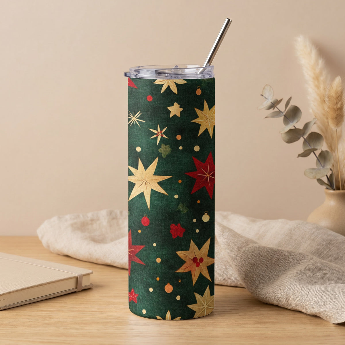 Green tumbler with a pattern of red and gold stars and festive ornaments.