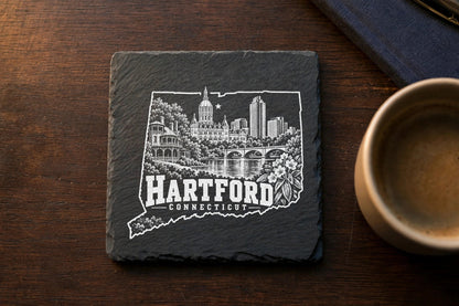 A square black slate coaster featuring an engraved white skyline design of Hartford, Connecticut.
