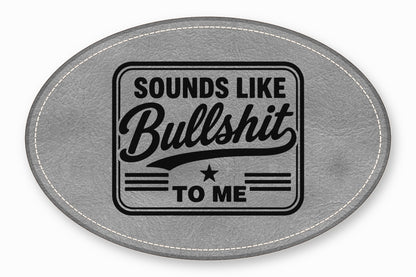 An oval gray leather patch with white stitched borders features the black engraved text SOUNDS LIKE BULLSHIT TO ME.