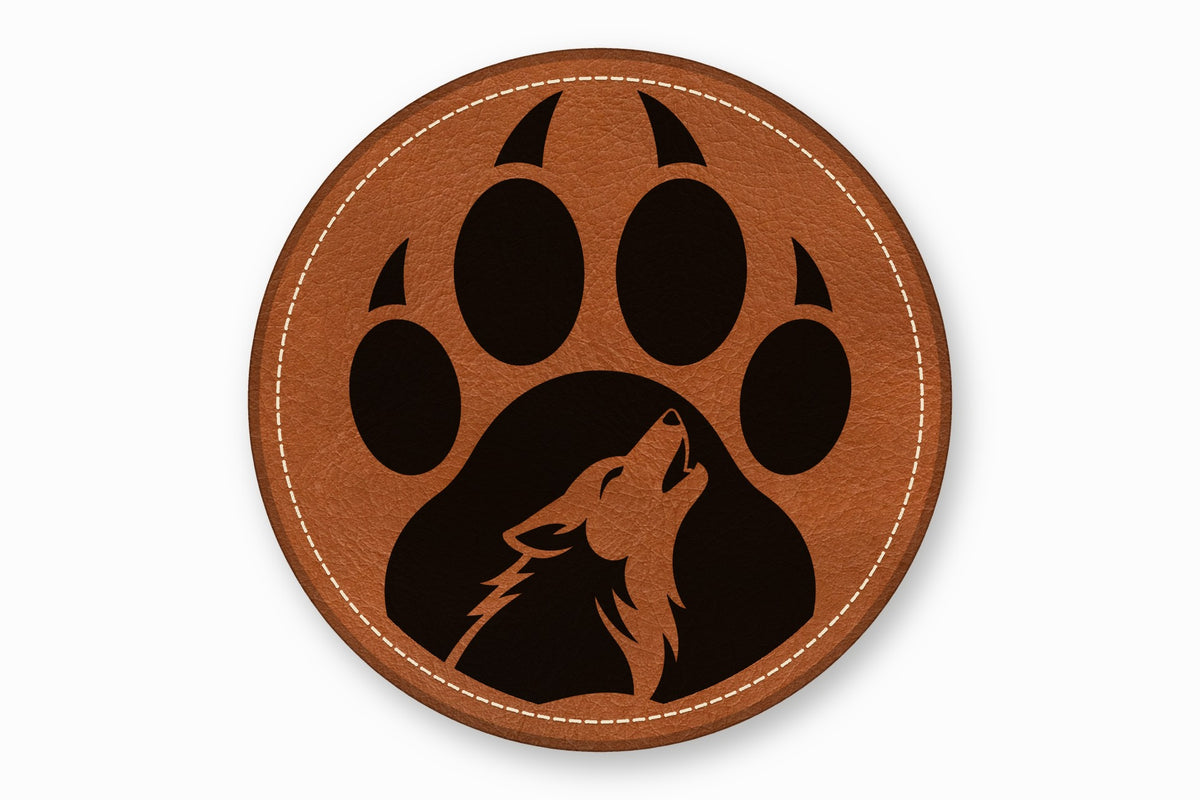 Round brown leather patch with white stitched border featuring a black paw print and howling wolf silhouette.