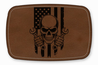 Brown leather patch featuring a black skull holding wrenches in front of an American flag.