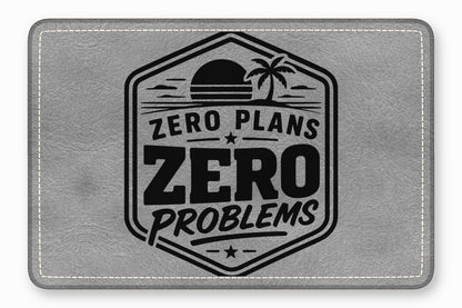 Grey leather patch with white stitched border and black stamped tropical design containing text ZERO PLANS ZERO PROBLEMS.