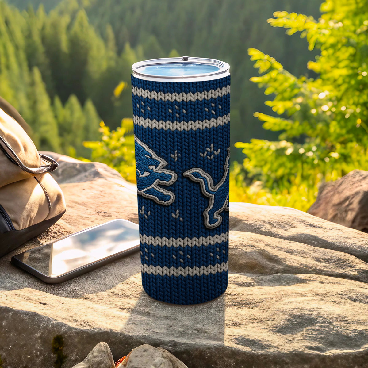 Detroit Lions knit tumbler with two lion logos on a rocky surface.