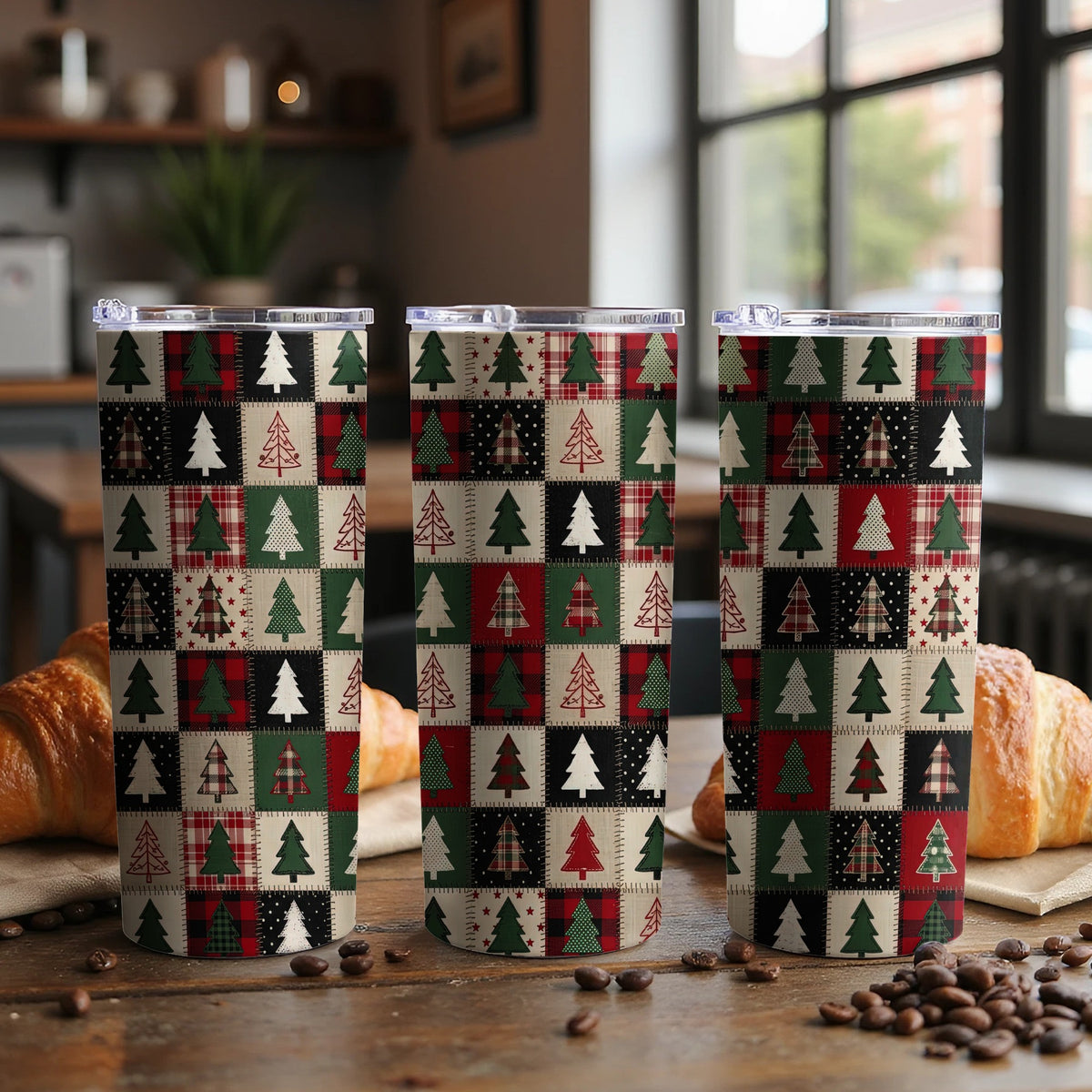 Three tumblers with a patchwork design of Christmas trees on a wooden table.