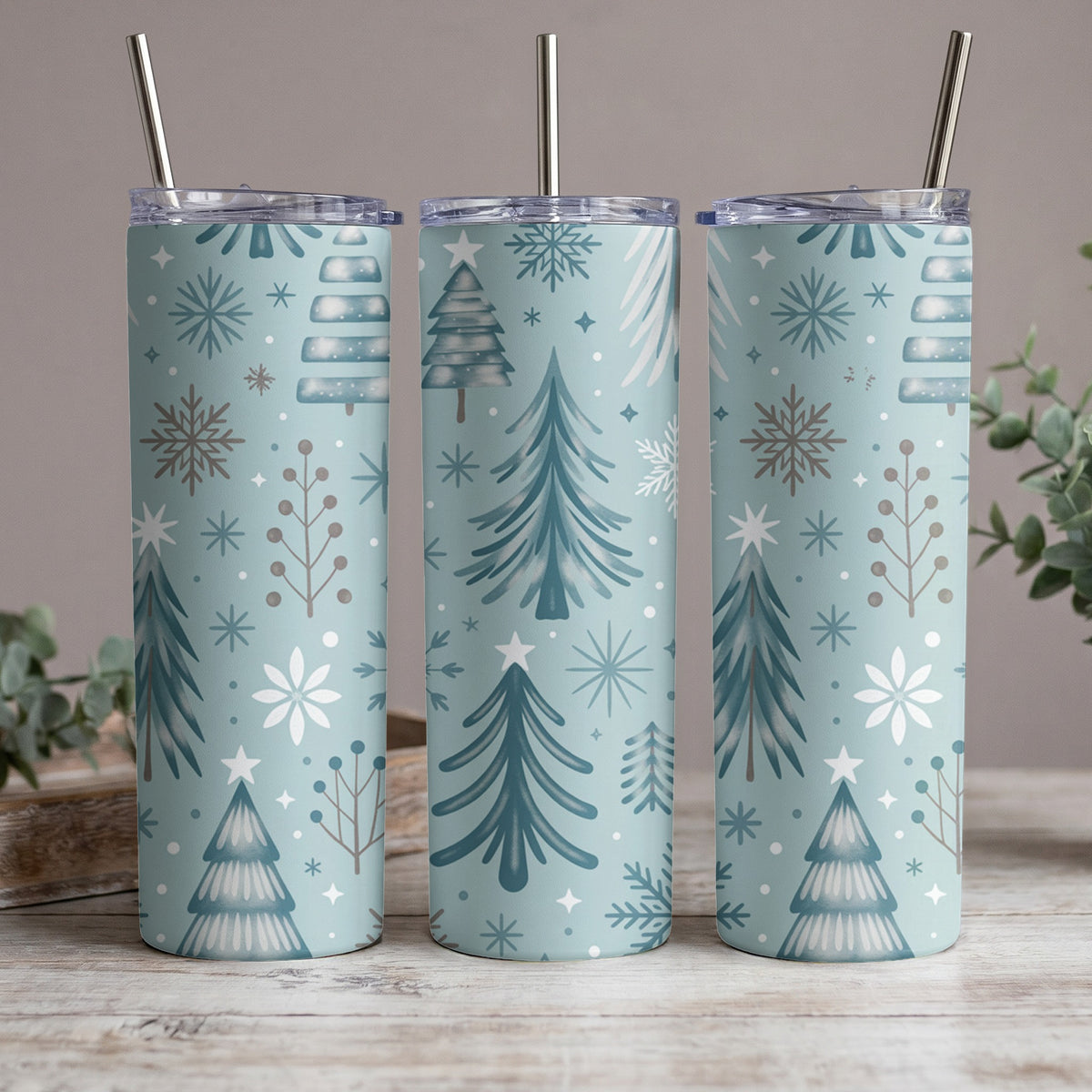 Three tumblers with a light blue background and a repeating Christmas tree and snowflake pattern.