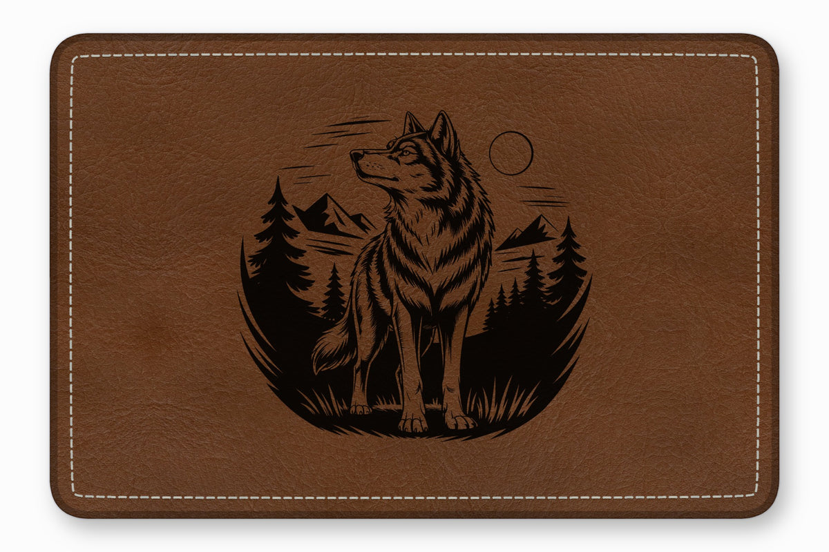 Brown leather desk mat with a black engraved design of a wolf, mountains, and pine trees.