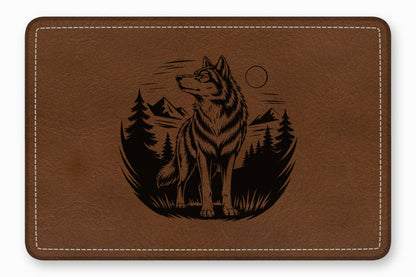 Brown leather desk mat with a black engraved design of a wolf, mountains, and pine trees.