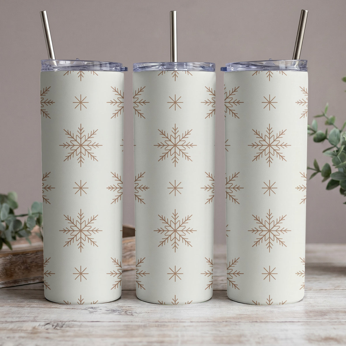 Three tumblers with a repeating brown snowflake pattern on a cream background.