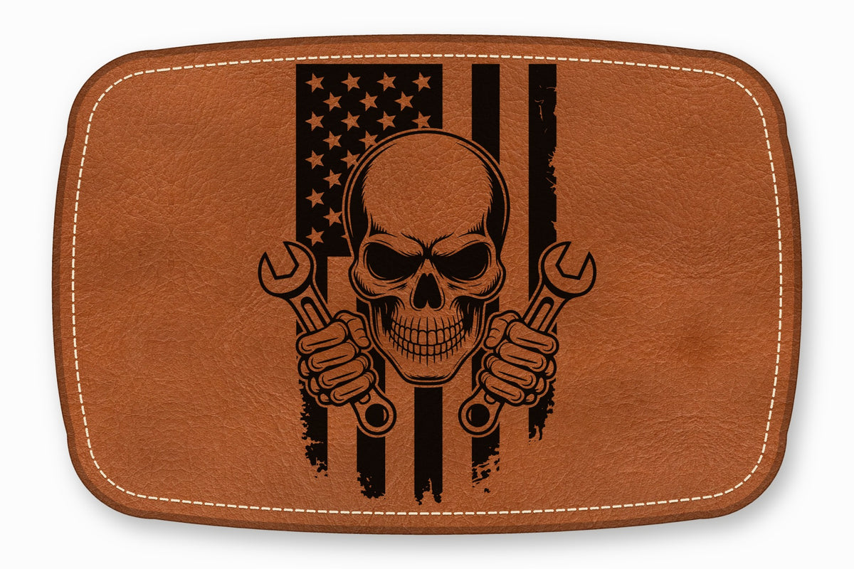 Brown leather patch with rounded corners featuring a skull holding two wrenches over a distressed American flag.