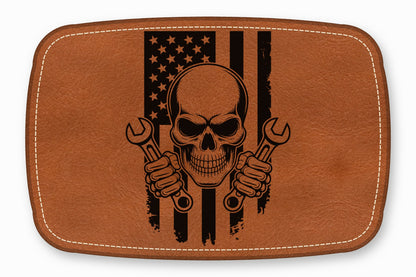 Brown leather patch with rounded corners featuring a skull holding two wrenches over a distressed American flag.