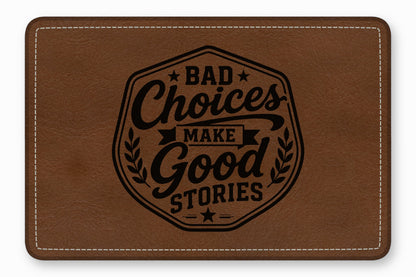 A brown faux leather patch with white stitching and the engraved text Bad Choices Make Good Stories.