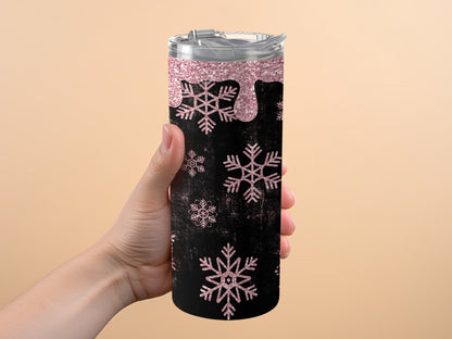 Black tumbler with pink glitter drips and snowflakes, held by a hand.