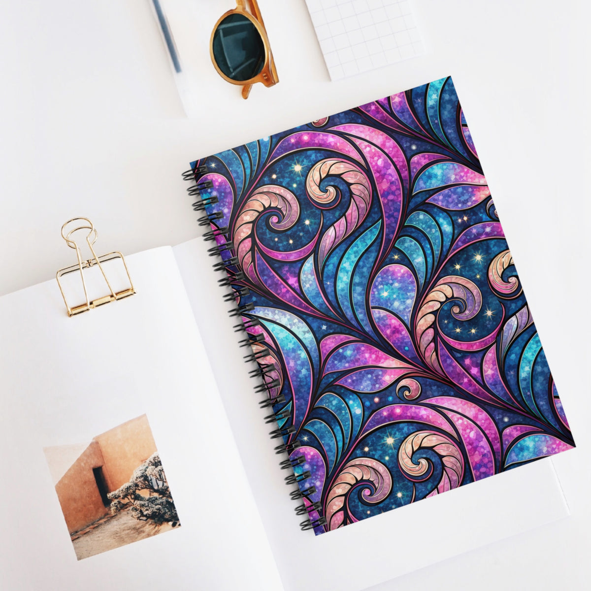 Spiral notebook with a stained-glass-inspired cosmic swirl design in pink and blue.