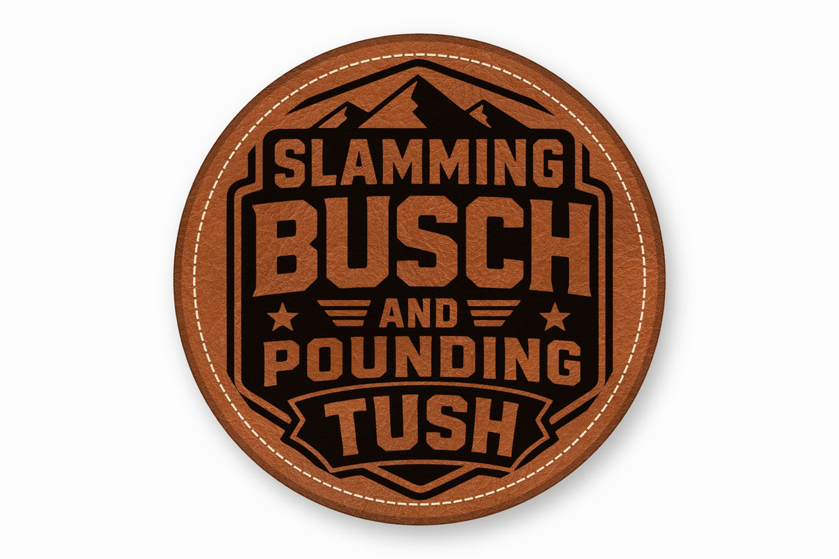 Round brown leather coaster with white stitched border, featuring a black mountain graphic and text reading SLAMMING BUSCH AND POUNDING TUSH.